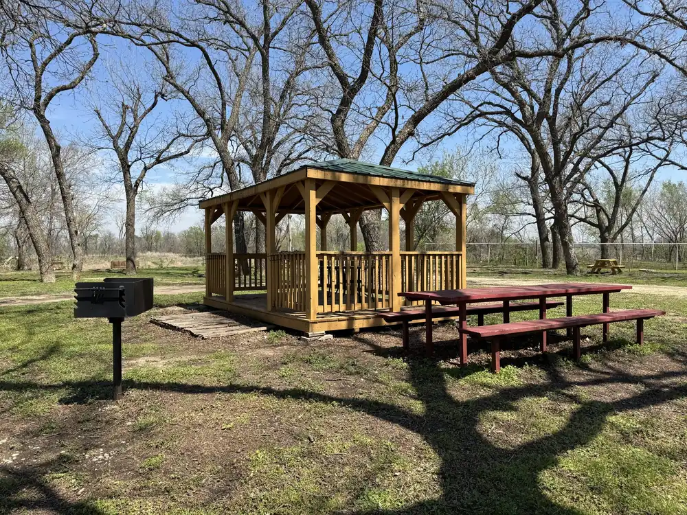 Covered pavilion with picnic tables and charcoal grill at Rivershire