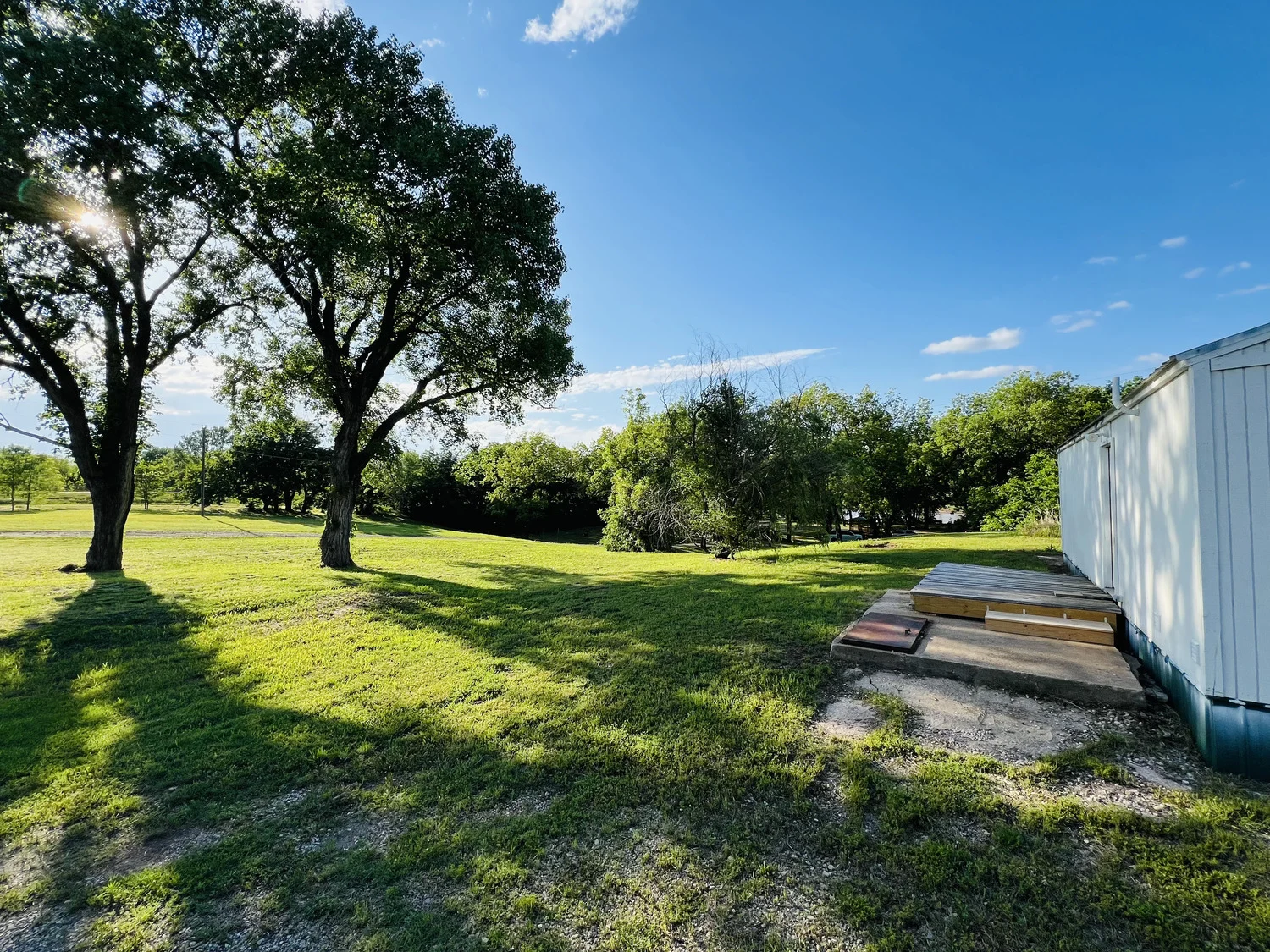 Shaded grass sites under mature trees at Rivershire RV Park, Ponca City