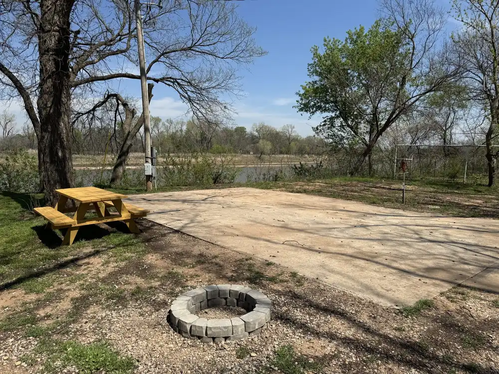 Riverfront RV site with fire pit and picnic table, river visible behind
